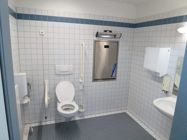 public-handicap-bathroom-with-toilet-and-undermount-sink-under-frameless-mirror-in-white-bathroom-wall-tiles.jpg